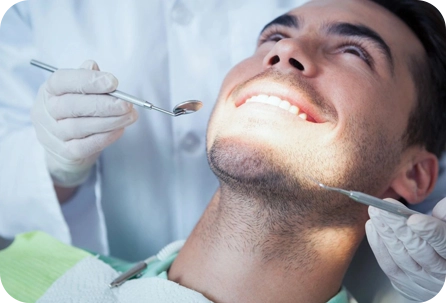 A man is getting his teeth checked by an dentist.